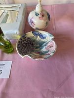 Photo of ceramic soap dispenser with floral design and matching shell-shaped dish with painted flowers and leaves