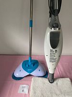 View of Shark steam mop and blue and white rotating scrub mop with microfiber pad and small white labeled item