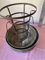 Circular metal mug holder atop wooden bowls, showcasing construction and size relative to a ruler