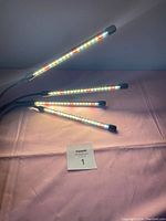 Four flexible LED light bars lit in various colors attached to single base.