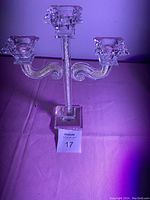 Clear crystal triple arm candle holder with square base and three curled arms.