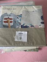 Close-up of packaged heat press mat with label showing size and some of the fabric tablecloth material beneath.