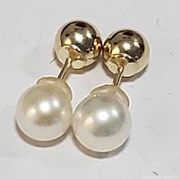 Pair of reversible stud earrings showing gold ball fronts with freshwater pearl backs