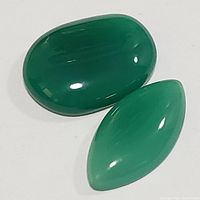 Two polished green onyx gemstones: one oval and one marquise shape, showing color and shape details.