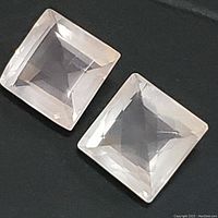Two square cut rose quartz gemstones placed side by side on a dark background.