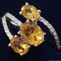 Close-up view of the sterling silver ring with three oval citrine stones in a split shank setting, showcasing the color and cut of the stones.