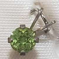 Close-up of one sterling silver earring with a round faceted green peridot held by four prongs.