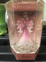 Front view of the hand-sculpted crystal angel figurine in clear packaging showing 22KT gold label and Lovingbox branding.