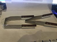 Set of two stainless steel cake cutters with wooden handles displayed on white background to show their shape and condition.