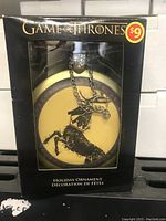 Boxed Game of Thrones holiday ornament with Baratheon sigil, showing original packaging and price sticker