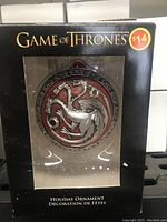 Front view of the metallic Game of Thrones holiday ornament featuring House Targaryen's three-headed dragon in original packaging with price tag.