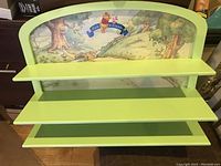 Full view of Pooh & Friends wall mount shelf with three light green shelves and illustrated backboard.