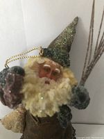 Close-up of Santa Claus figure's face, showing glittery hat, curly blond beard and facial details
