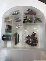 Plastic organizer case with multiple compartments holding various rotary tool accessory bits and pieces.