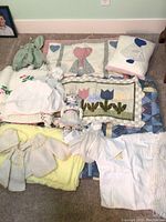 Overall image displaying all items in the lot including quilts, pillow sham, knit blankets, baby clothes and soft dolls.