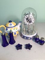 Front view of all items including domed clock, teapot, blue glass shakers and star-shaped items