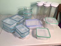 Photo showing a variety of food storage containers, including Pyrex glass bowls and Rubbermaid plastic containers with colored lids and three tall canisters.