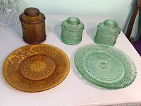 Set of items including two large glass platters (one green, one amber) and three canisters (two green, one amber) displayed on table