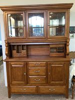 Full front view of solid oak hutch with three leaded glass doors on upper cabinet, and drawers and cabinets below.