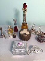 Entire lot of vintage perfume bottles, powder container, small clock, and bell as seen from the front.