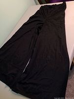 Full view of the black slinky bell bottom hostess pants showing the wide leg and flowing fabric.