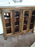 Front view of walnut display cabinet with four glass doors and carved base detailing.