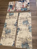 Top view of three rugs laid on floor including two similar sized fatigue rugs and one smaller floor rug
