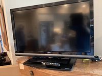 Full front view of the 42 inch Vizio flat screen TV on its swivel stand showing the screen, soundbar, and remote on the stand base.