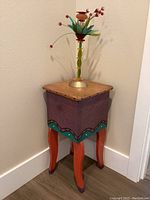 Plant stand front corner angle showing colorful painted design and curved legs with candle holder on top