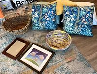 View showing all items including throw pillows with blue floral bird pattern, mustard and light-colored pillows, two woven baskets on the floor, and two picture frames with one displaying a pig print.