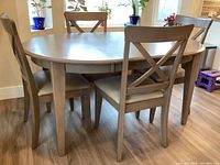 Front angle view of oval table with four chairs in room