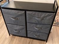 Front view of black metal storage unit with five grey fabric totes in two columns