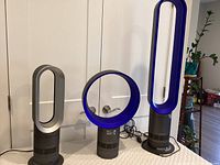 Front view of all three Dyson bladeless units: silver tower fan, blue desk fan, and blue tower heater-fan