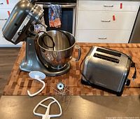 Overall view of KitchenAid stand mixer, attachments and Cuisinart toaster on butcher block countertop