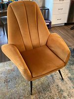 Front three-quarter view of golden orange velvet armchair on area rug