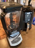 Ninja blender and cooker set placed side by side on a metal surface.