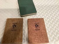 Top view of two vintage nursing books with fabric covers and nurse illustrations placed on white quilted surface