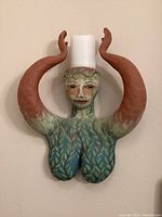 Front view of the ceramic lady candle holder mounted on the wall with candle inserted on top.