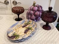 Overall lot image showing two purple glass candy dishes, large purple grape ceramic cookie jar, and hand-painted grape platter