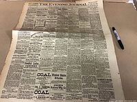 Image showing the full page of The Evening Journal newspaper laid flat with a marker for scale.