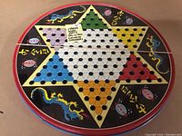 Top view of the 1960s round tin litho Chinese Checkers board with colorful star pattern and Chinese dragon and characters.