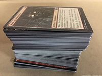 Side view of a thick stack of over 200 Magic the Gathering trading cards, showing card edges and thickness.