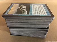 Side profile showing a thick stack of Magic: The Gathering cards with visible card edges and typical MTG blue card backs.