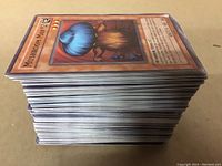 Stack of Yu-Gi-Oh! cards showing edge of cards with Mushroom Man Lv4 card on top.