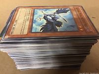 Stack of Yu-Gi-Oh cards showing edges and part of the top card (Harpy's Feather Duster)