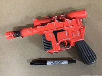 Photo of Han Solo electronic blaster toy showing full gun with red and black plastic body.