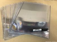 Group of 10 clear rigid plastic toploader sleeves for 11x14 sized items, stacked and fanned out with a marker for scale.