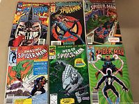 Photo of six Spider-Man comic books showing front cover art with Spider-Man in various suits and Marvel characters