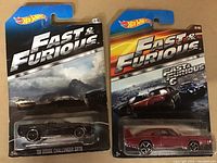 Two Hot Wheels Fast & Furious sealed diecast cars in packaging, showing 2008 Dodge Challenger SRT8 and red muscle car.