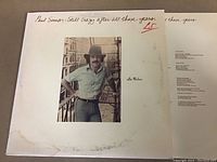 Photo of Paul Simon LP album cover "Still Crazy After All These Years" with visible wear, handwritten text, and a photo of Paul Simon.